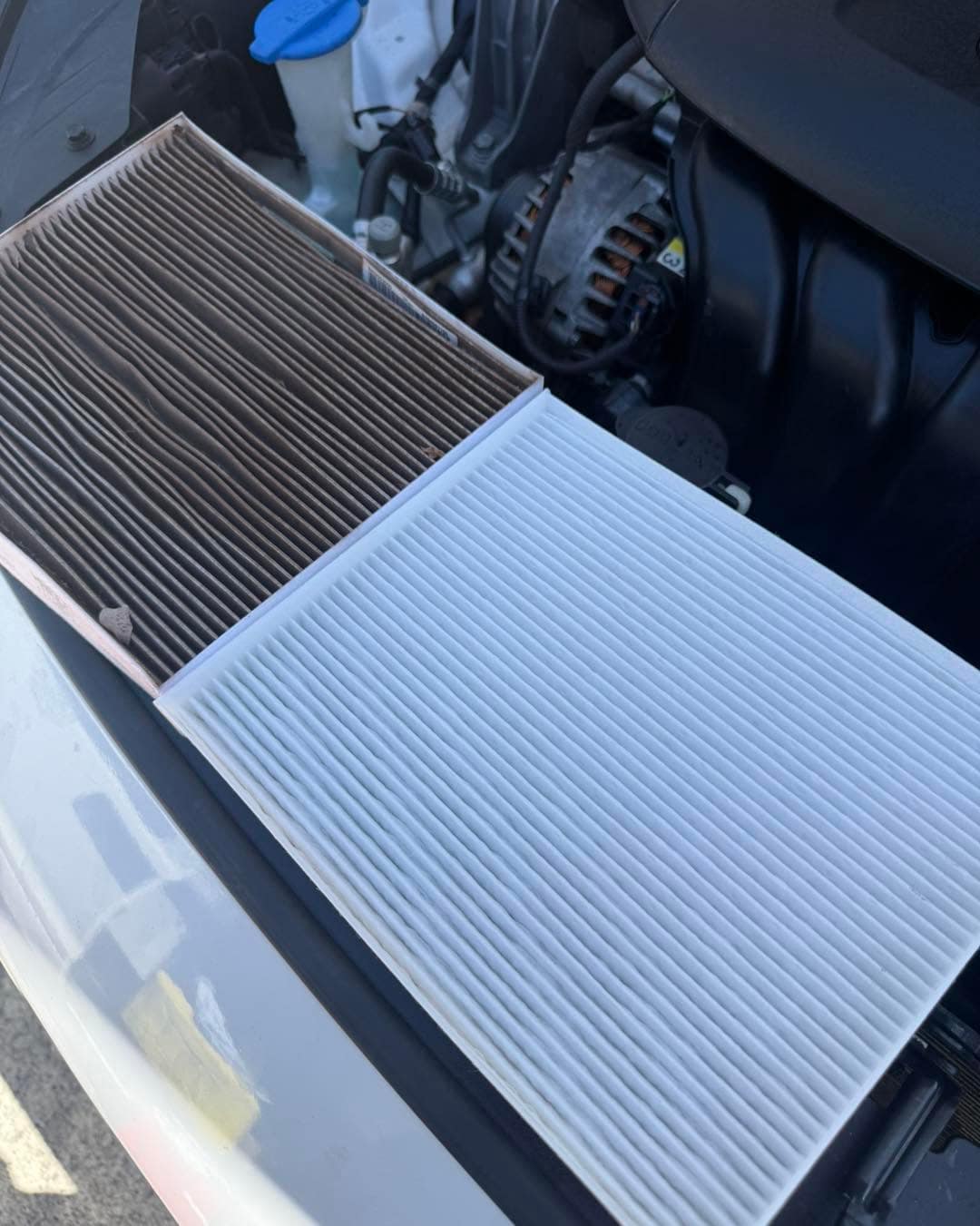 Two cabin filters side by side on a car: the old one dark and clogged on the left, the new one clean and white on the right.